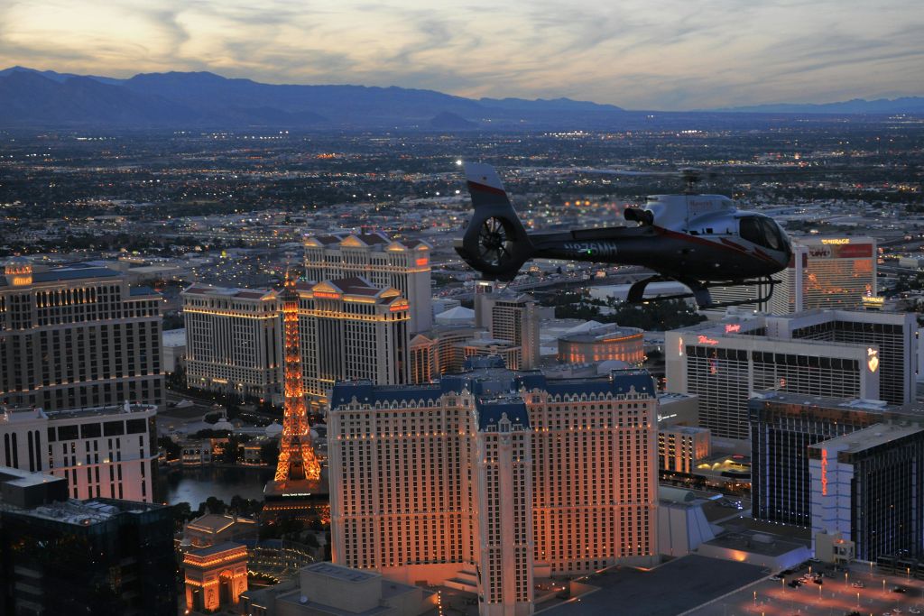 해질 무렵 빛나는 도시 풍경 위를 날아다니는 헬리콥터는 높은 건물과 에펠탑 복제품을 갖추고 있습니다.