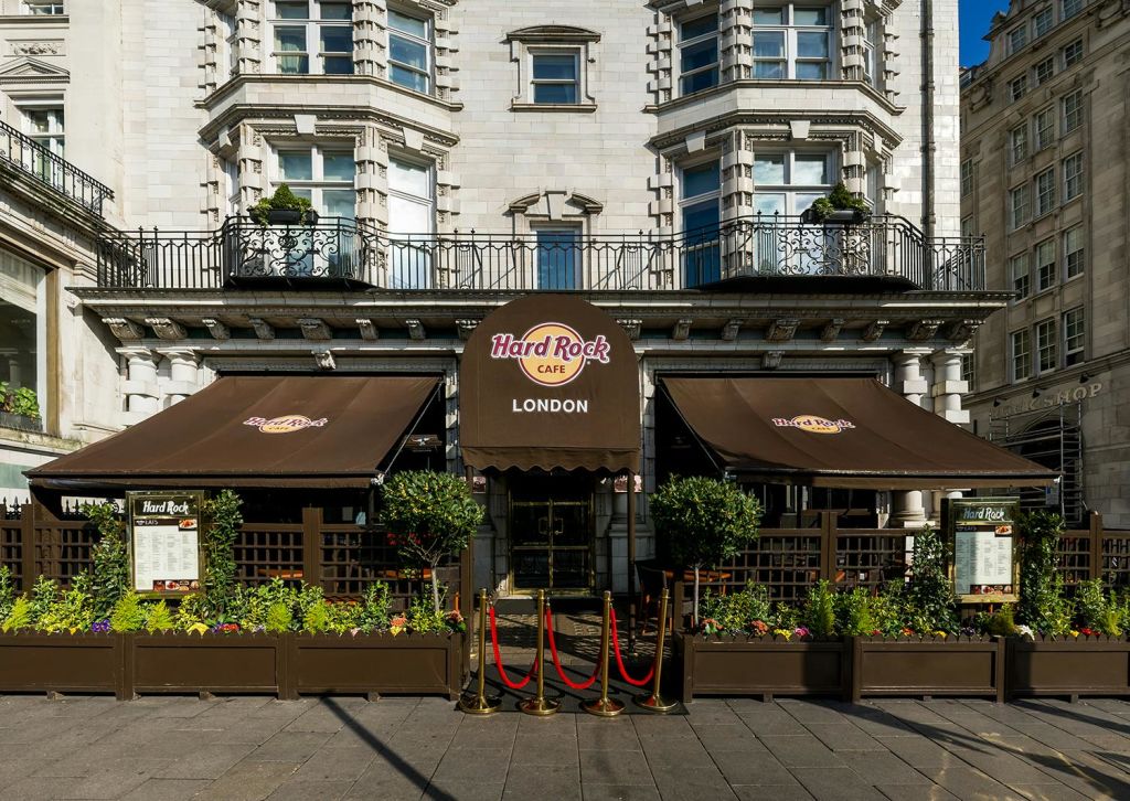 갈색 차양, 화분, 입구로 이어지는 빨간 밧줄이 있는 하드록 카페 런던의 외관.