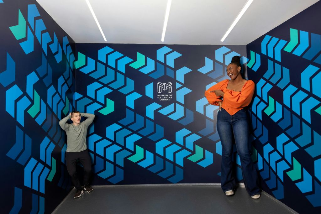 디트로이트의 환상 박물관에서 두 사람이 착시 벽 예술과 교감하고 있습니다.