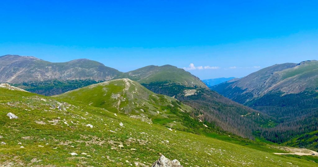 맑고 푸른 하늘 아래 푸른 언덕과 먼 산의 경치.