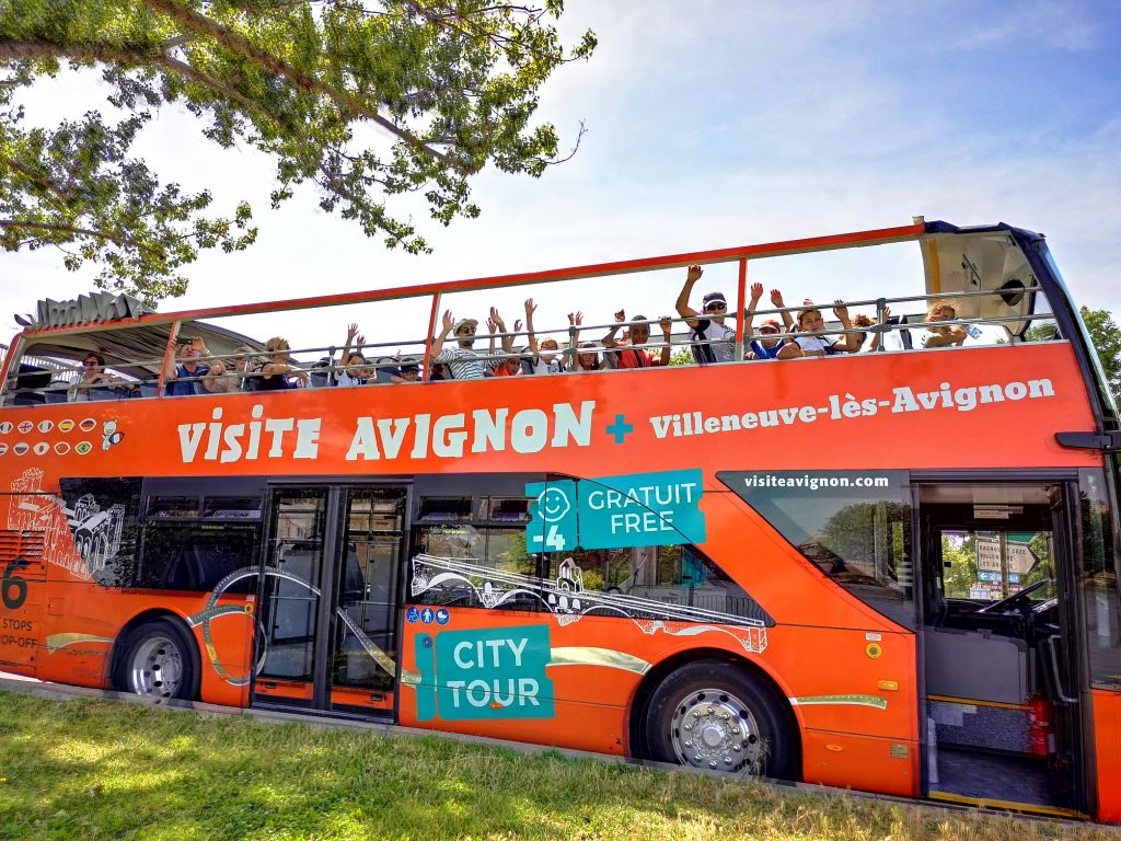 "Visite Avignon + Villeneuve-lès-Avignon" 이라는 라벨이 붙은 밝은 빨간색 2층 투어 버스입니다.