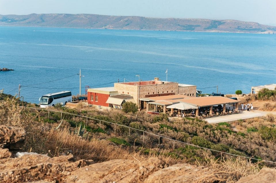 산을 배경으로 물 근처의 건물들이 밀집해 있는 해안 전망과 근처에 버스가 주차되어 있습니다.