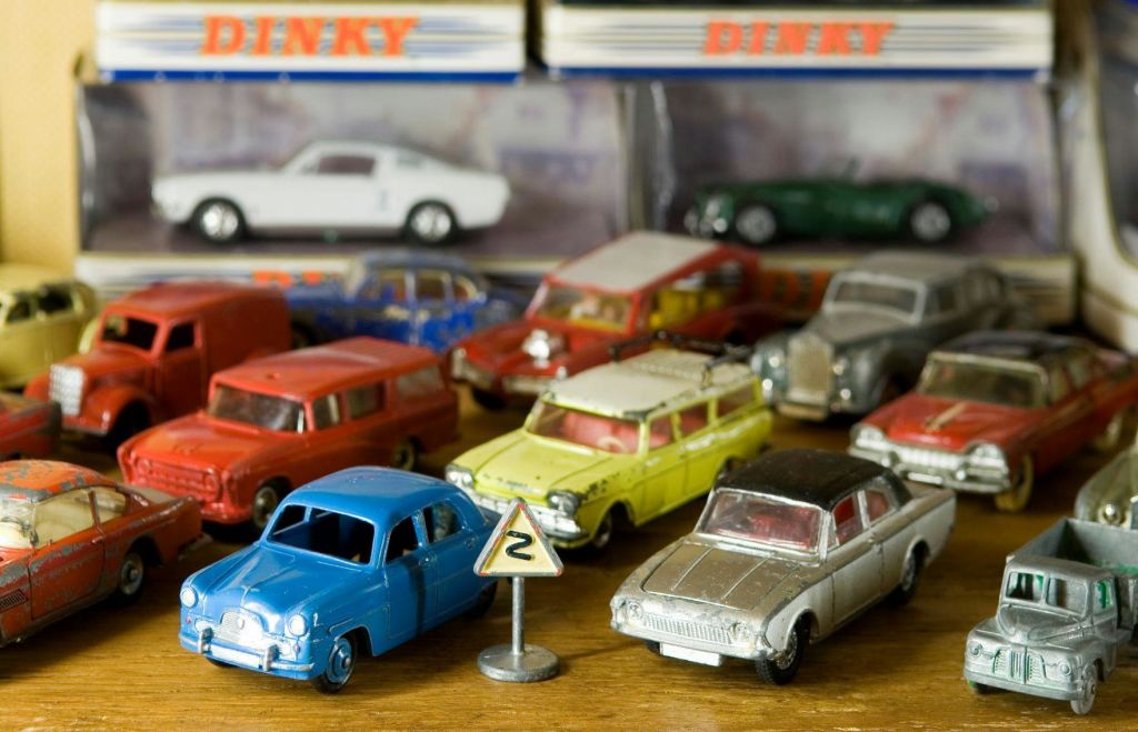 나무 표면에 다양한 색상의 빈티지 장난감 자동차 모듬으로 작은 도로 표지판과 상자형 장난감 자동차를 배경으로 합니다.