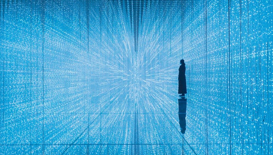 한 사람이 파란 불빛이 비추는 매혹적인 방 한가운데 서서 터널과 같은 무한 패턴 효과를 연출합니다.