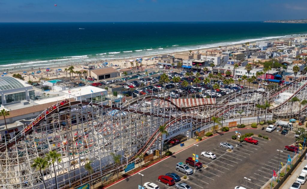 나무 롤러코스터, 주차장, 해변을 찾는 사람들, 바다를 배경으로 벨몬트 공원의 공중 전망을 감상할 수 있습니다.