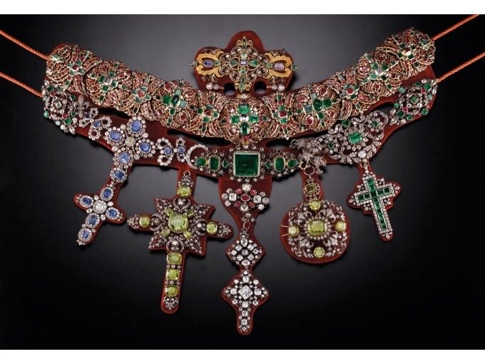 화려한 보석과 정교한 금속 세공물로 장식된 화려한 목걸이로 크고 정교한 펜던트가 여러 개 있습니다.