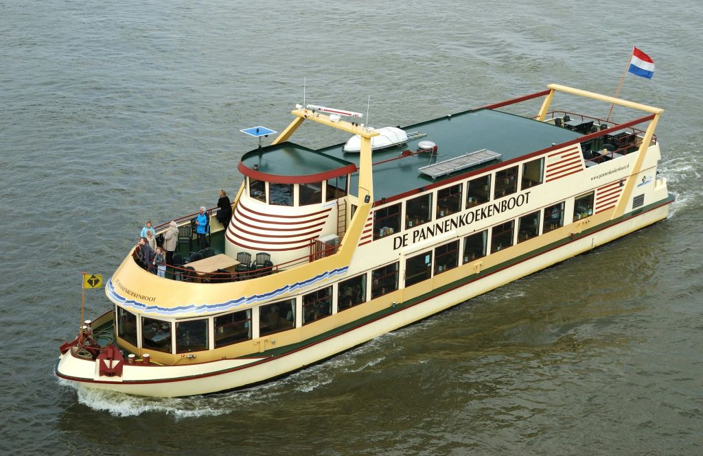 "De Pannenkoekenboot" 라는 이름의 보트가 갑판과 창문에서 승객들과 함께 물 위를 유람합니다.