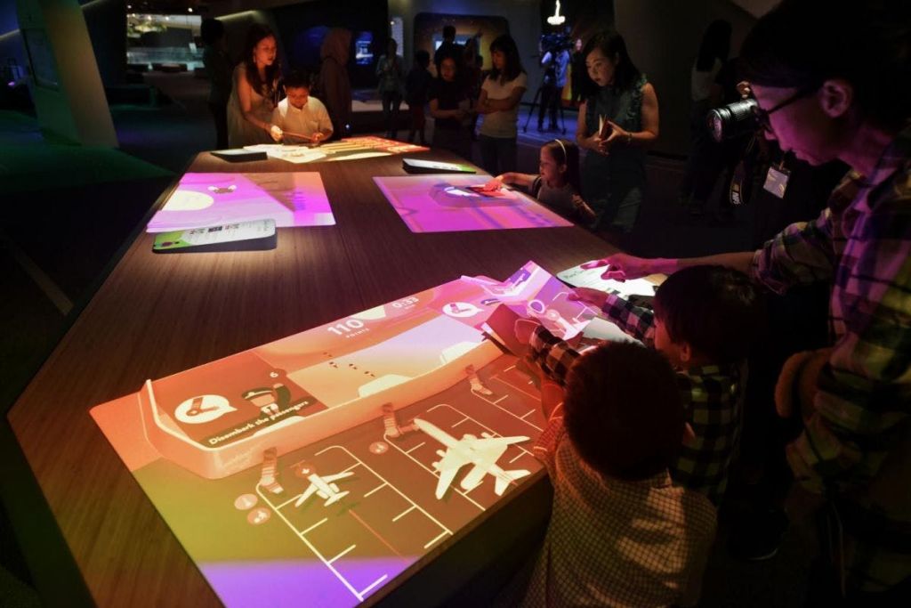 조명이 어두운 방에서 그래픽과 정보를 표시하는 조명 터치스크린과 상호 작용하는 사람들.