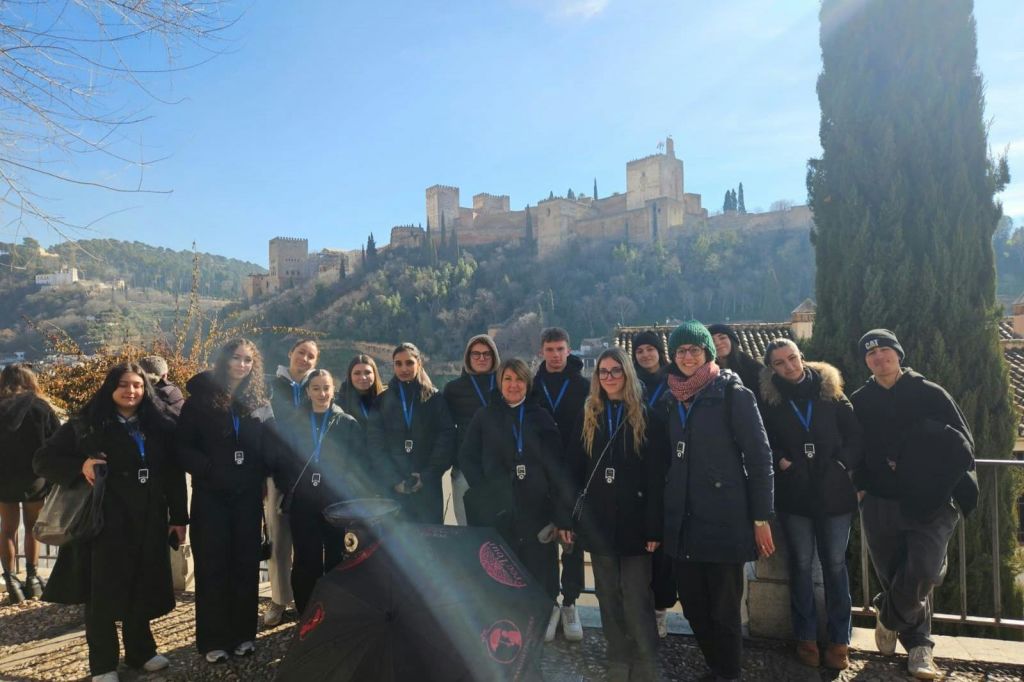 맑은 하늘 아래 언덕을 배경으로 유서 깊은 성을 배경으로 야외 포즈를 취하고 있는 한 무리의 사람들.