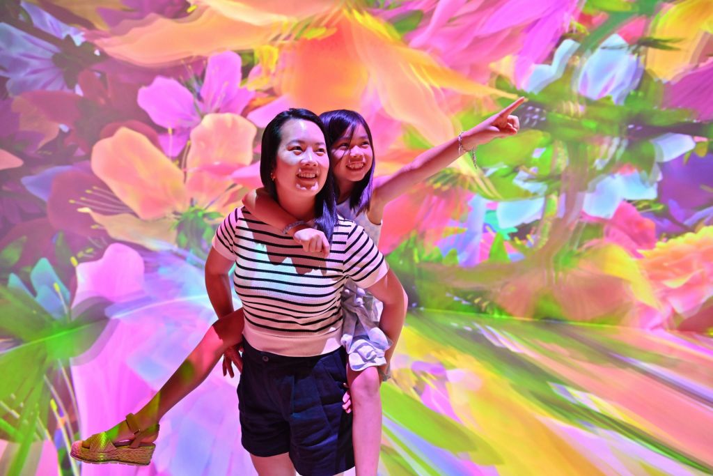 화려하고 추상적인 꽃무늬의 생동감 넘치는 배경을 배경으로 즐거운 포즈를 취하는 두 사람.