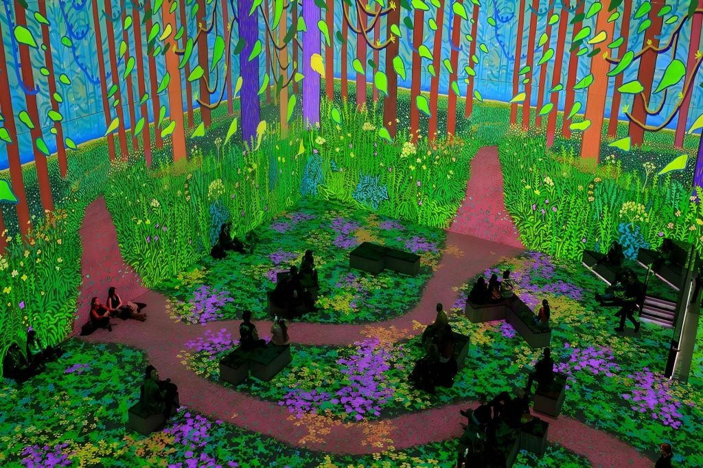 다채로운 숲 장면을 실감나게 디지털로 투영할 수 있는 객실로, 사람들이 벤치에 앉아 인테리어를 감상할 수 있습니다.