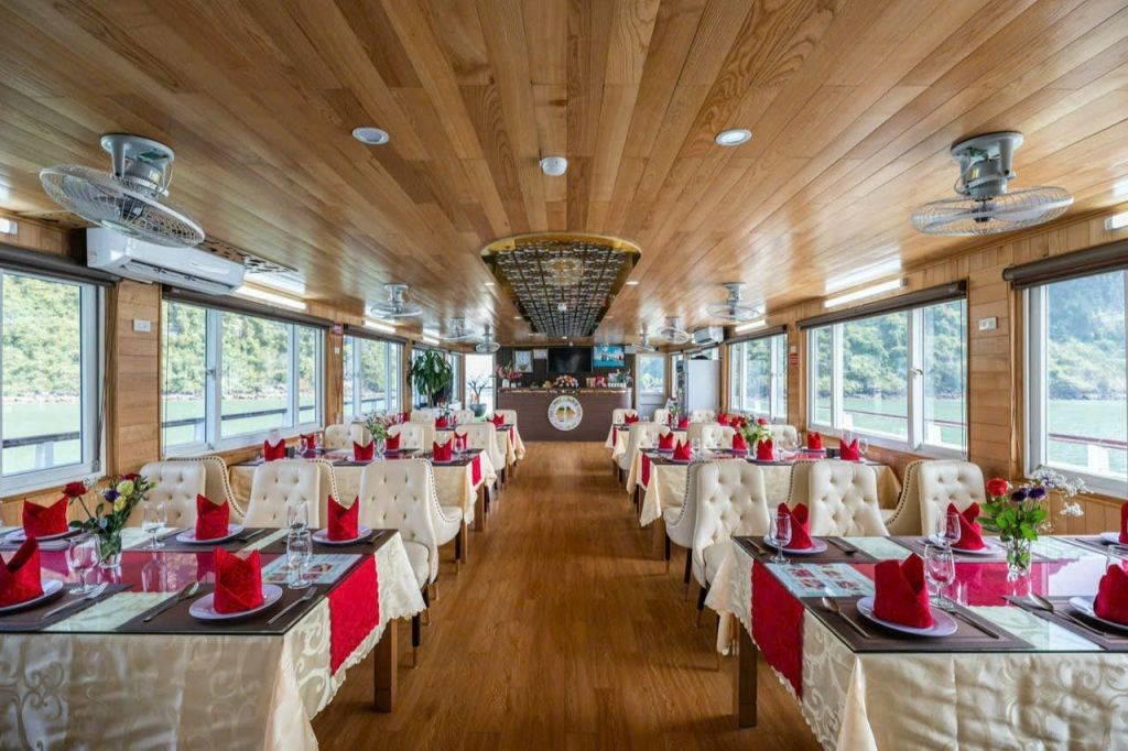 나무 장식, 빨간색과 흰색 테이블 설정, 쿠션 의자, 대형 창문, 바 카운터가 있는 보트의 우아한 식사 공간.