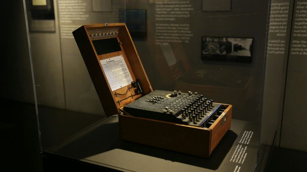 목재 케이스의 수수께끼 기계가 박물관 전시물에 전시되어 있으며, 뚜껑 안쪽에 정보 텍스트가 보입니다.