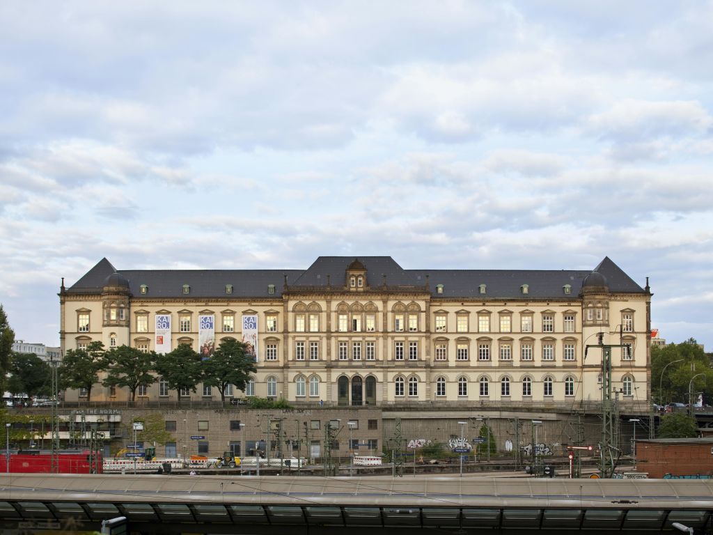 수많은 창문과 장식적인 건축 디테일이 있는 크고 유서 깊은 건물이 부분적으로 흐린 하늘 아래 서 있습니다.