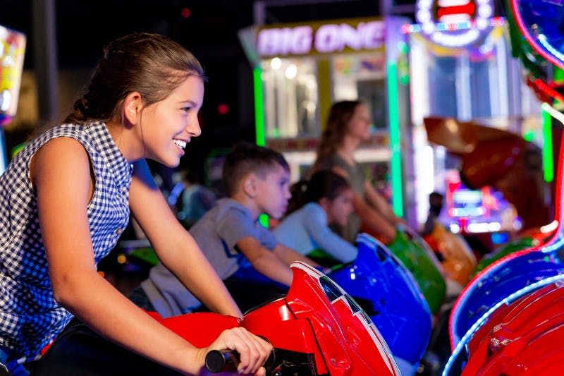 아케이드 오토바이 레이싱 게임에서 미소를 짓고 노는 아이들.
