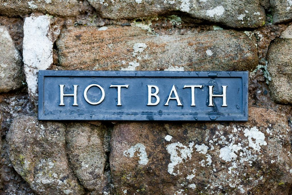 질감이 살아있는 돌담에 '온탕' 이라고 적힌 간판이 걸려 있습니다.