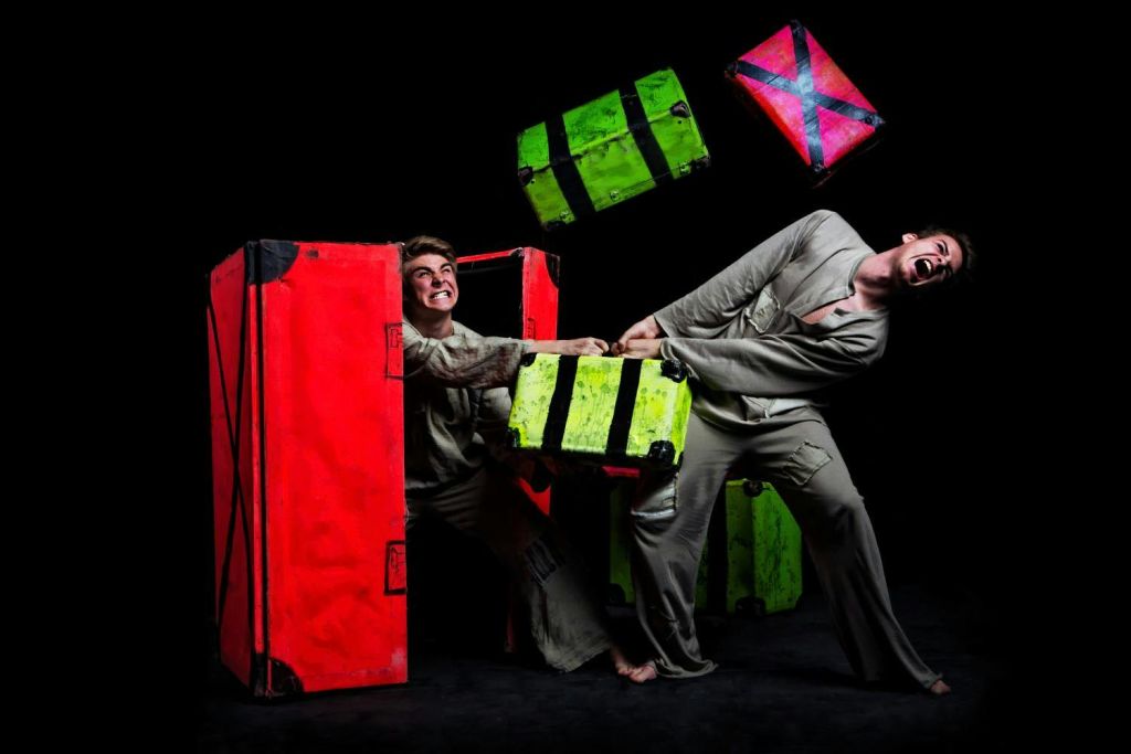 밝은 색상의 상자를 당기는 두 사람. 하나는 빨간색이고 다른 하나는 초록색입니다. 어두운 배경을 배경으로 말이죠.