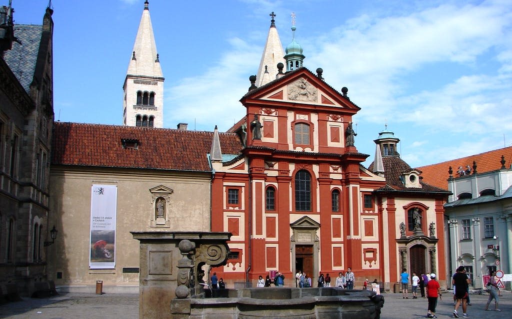 빨간색과 흰색 외관, 높은 타워, 앞쪽에 분수가 있고 사람들이 앞을 걷고 있는 유서 깊은 교회.