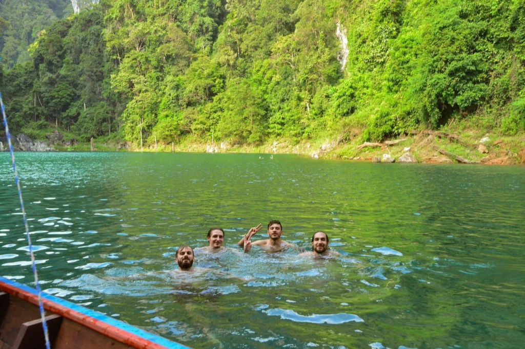 푸른 나무와 절벽으로 둘러싸인 호수에서 4명이 수영하고 있습니다.