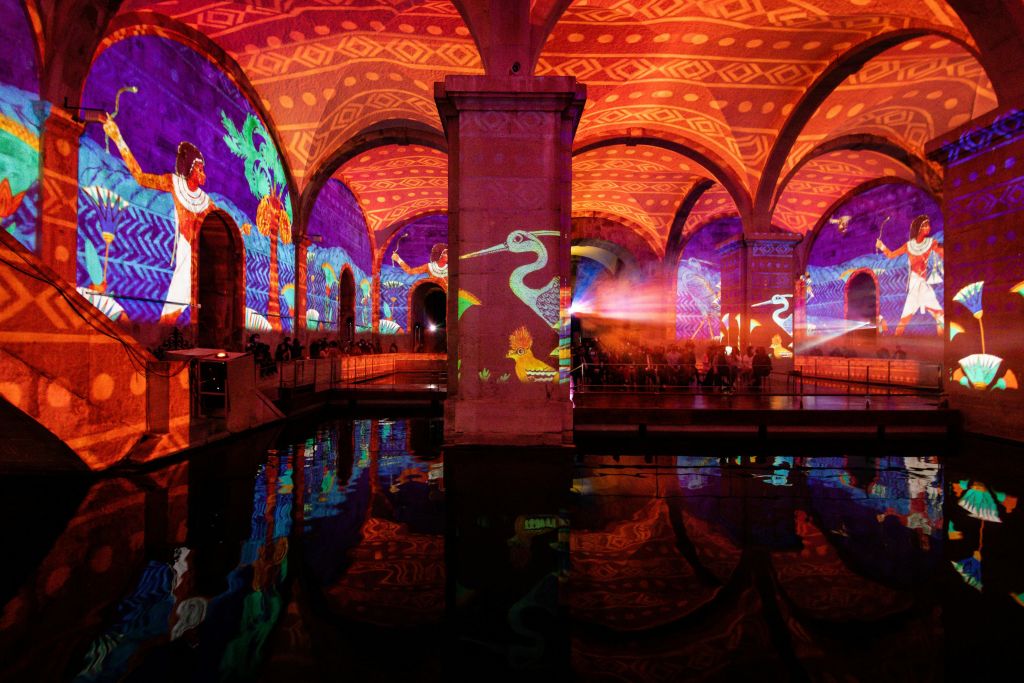 벽과 천장에 화려하고 생동감 넘치는 투사가 돋보이는 아치형 지하 공간으로, 아래 물에 반사됩니다.