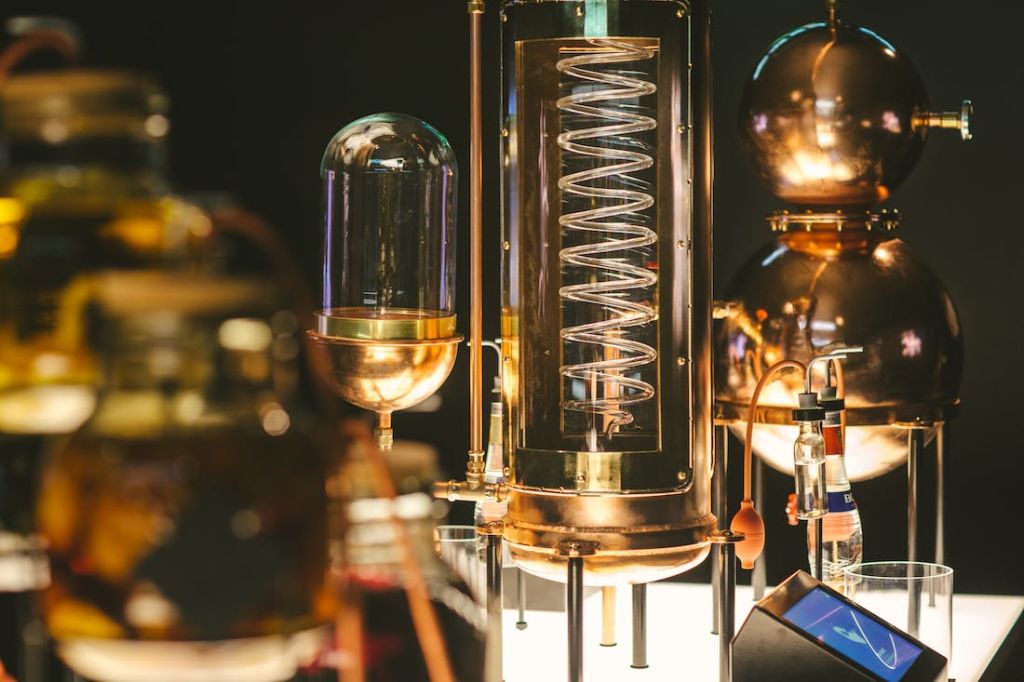 유리 돔, 구리 코일 및 어두운 배경의 금속 구조물이 특징인 빈티지 과학 실험실 장비의 클로즈업.