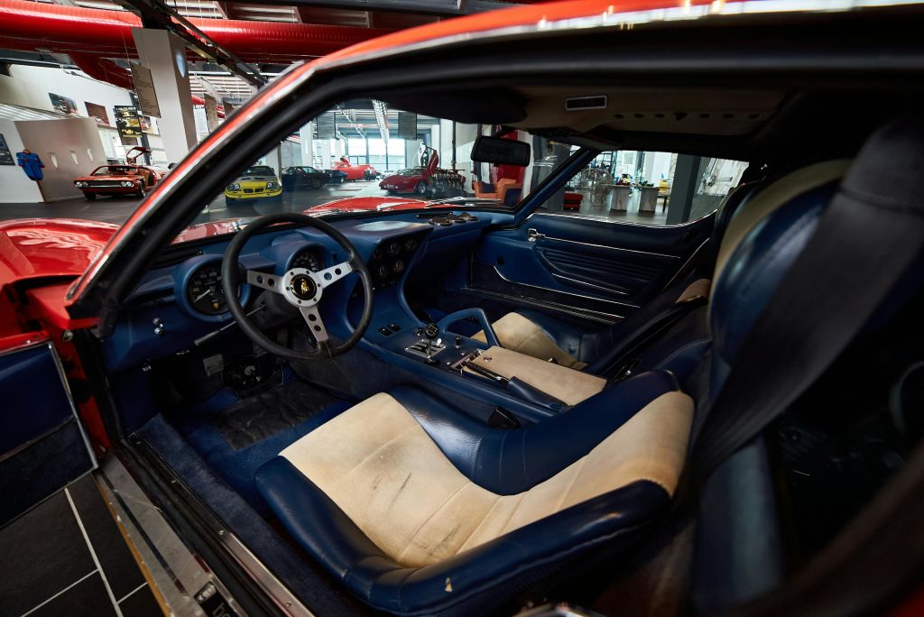 파란색과 베이지색 가죽 시트와 검은색 스티어링 휠이 있는 빈티지 스포츠카의 내부. 배경의 차고 설정.