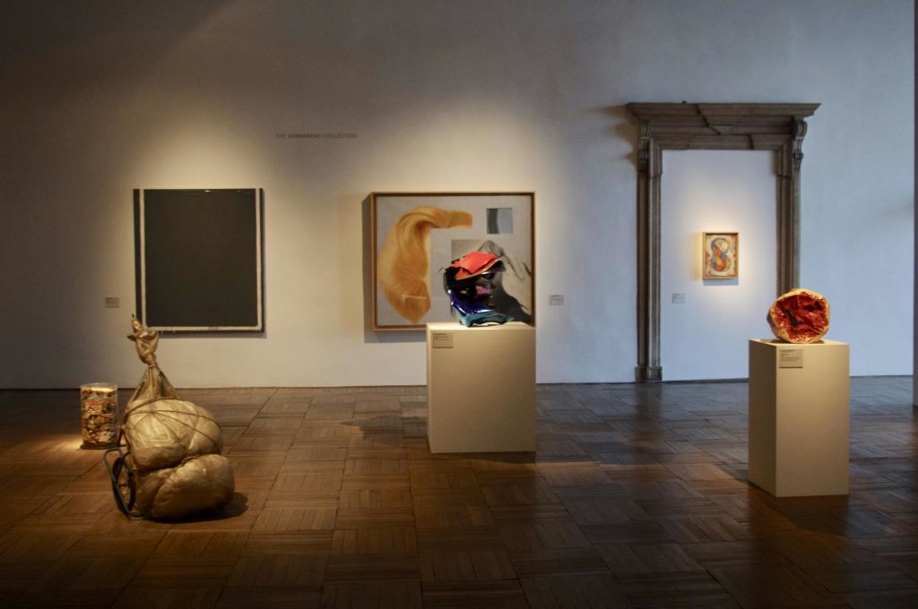 추상화, 주름 장식의 금속 조각, 황금 쿠션 조각 등 현대 미술 작품이 전시된 갤러리.