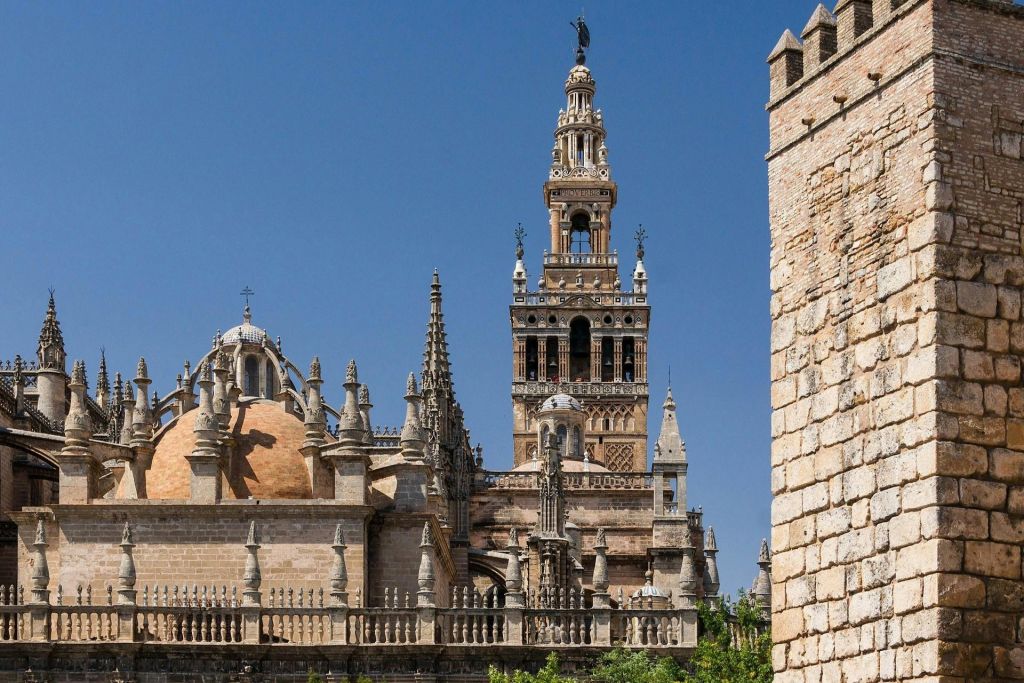 낮은 각도에서 바라보는 맑고 푸른 하늘 아래 화려한 첨탑과 높은 종탑이 있는 유서 깊은 대성당입니다.