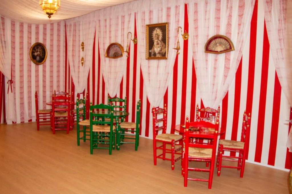 빨간색과 흰색 줄무늬 벽, 나무 의자, 액자에 담긴 예술품이 있는 장식된 방입니다.