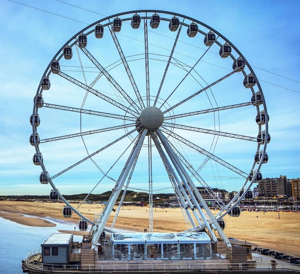 건물과 맑고 푸른 하늘을 배경으로 모래사장이 펼쳐진 부두의 대형 관람차.