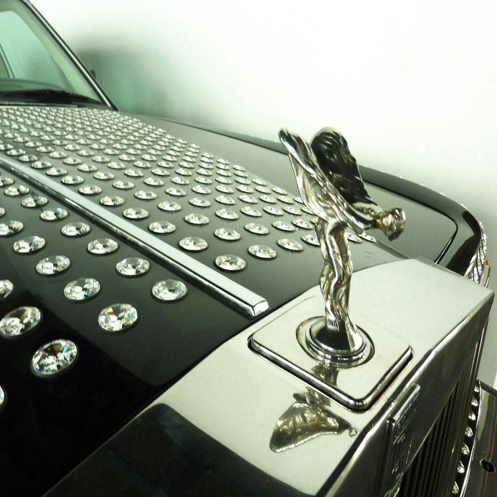 은상과 커다란 모조 다이아몬드로 덮인 후드가 특징인 자동차 후드 장식과 그릴의 클로즈업.