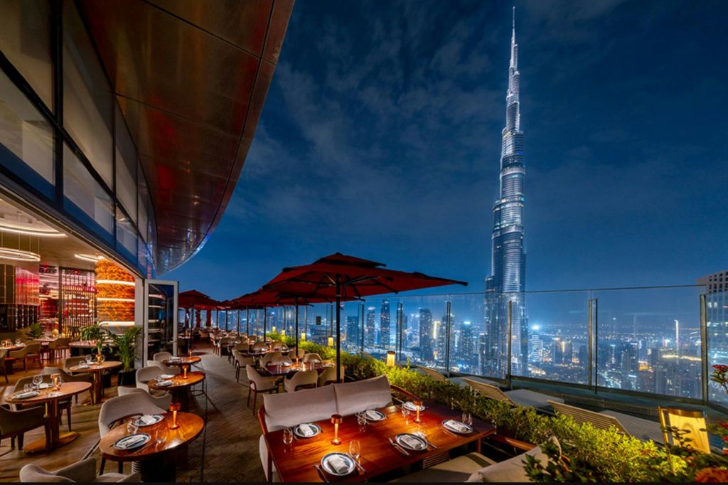 밤에는 도시의 스카이라인이 내려다보이는 야외 좌석과 빨간 우산을 갖춘 옥상 레스토랑으로, 높은 고층 빌딩이 있습니다.