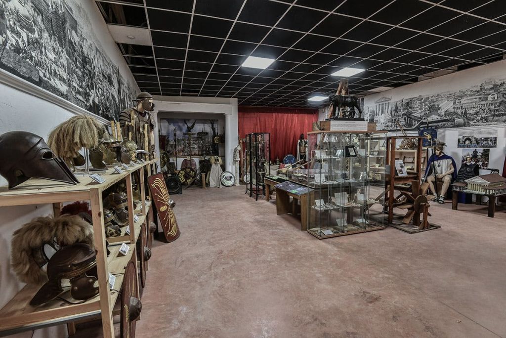 헬멧, 방패, 유리 진열장, 벽에 걸린 벽화 등 역사적 유물로 가득한 방.
