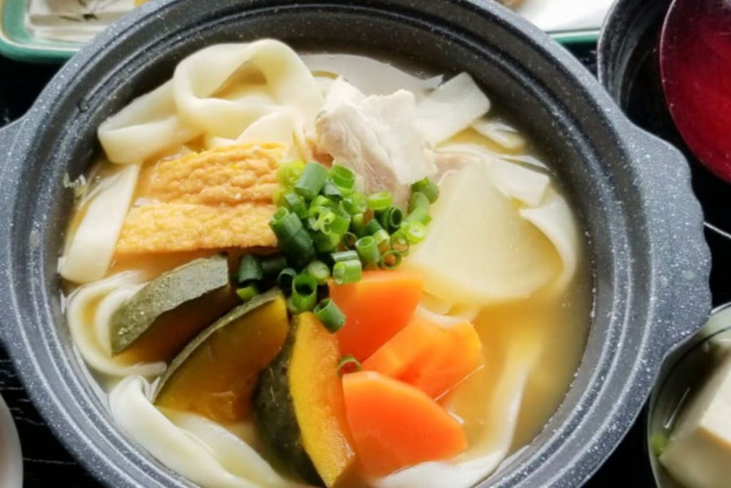 담백한 육수에 국수, 채소 썬 것, 파, 두부를 곁들인 국물 한 그릇.