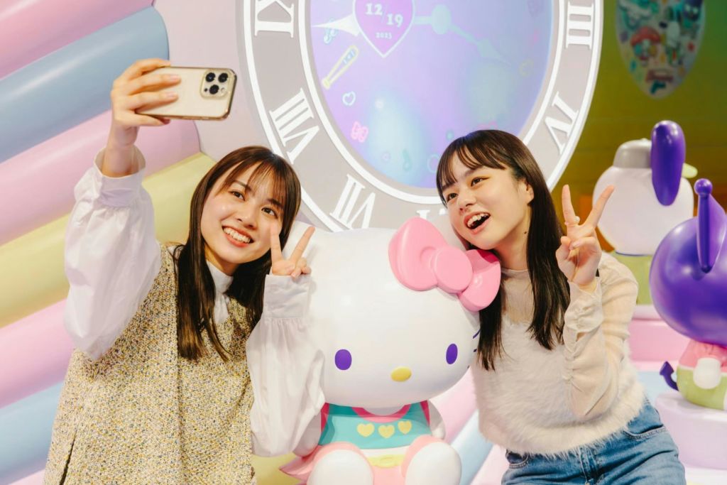 헬로키티 동상과 함께 시계를 배경으로 다채로운 포즈를 취하고 있는 두 사람.