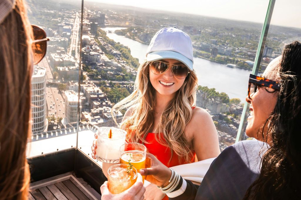 도시 풍경과 강을 배경으로 옥상에서 칵테일을 즐기며 건배하는 두 사람.