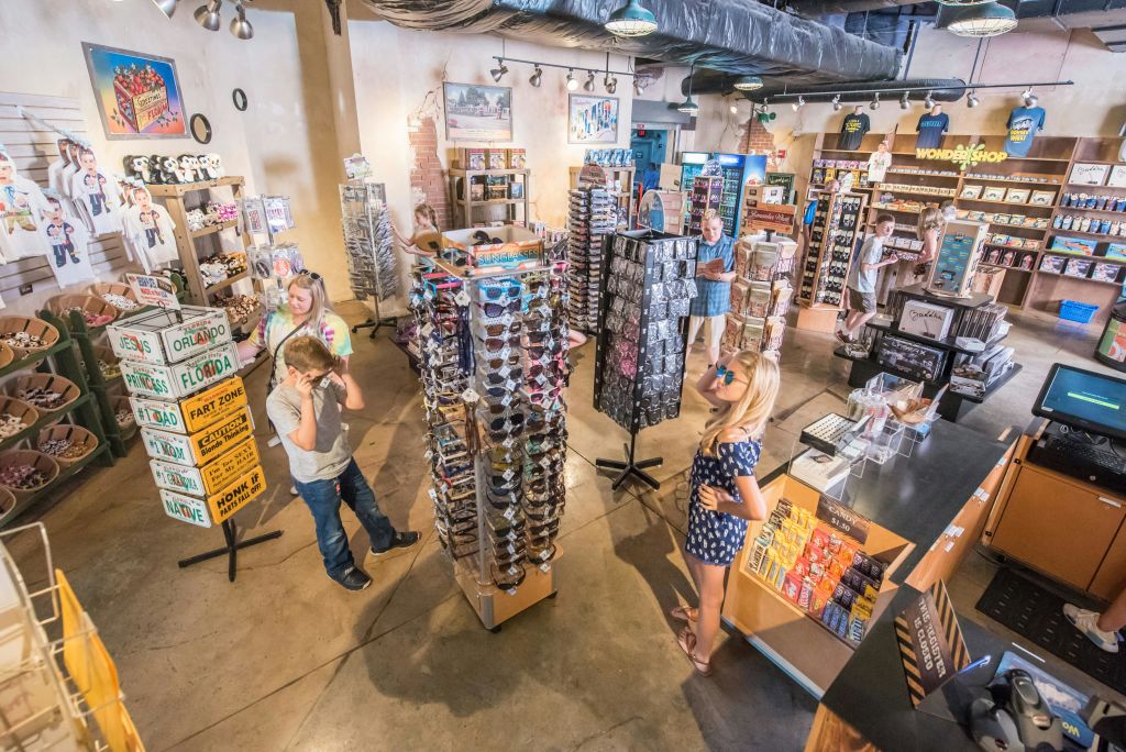 사람들은 선글라스, 기념품, 다양한 물품이 진열된 밝은 색상의 선물 가게를 둘러봅니다.