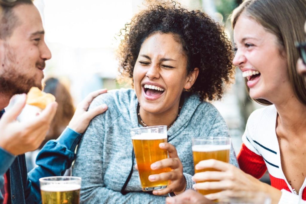 한 무리의 친구들이 야외에서 웃으며 맥주잔을 들고 있습니다.