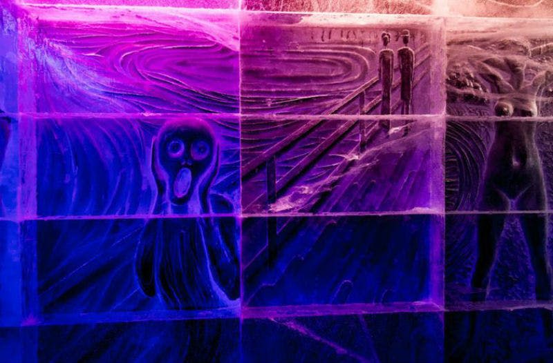 에드바르트 뭉크 (Edvard Munch) 의 "비명 (The Scream)" 의 얼음 조각이 보라색과 파란색 조명으로 비춰지며 충격적인 표정의 인물을 묘사합니다.