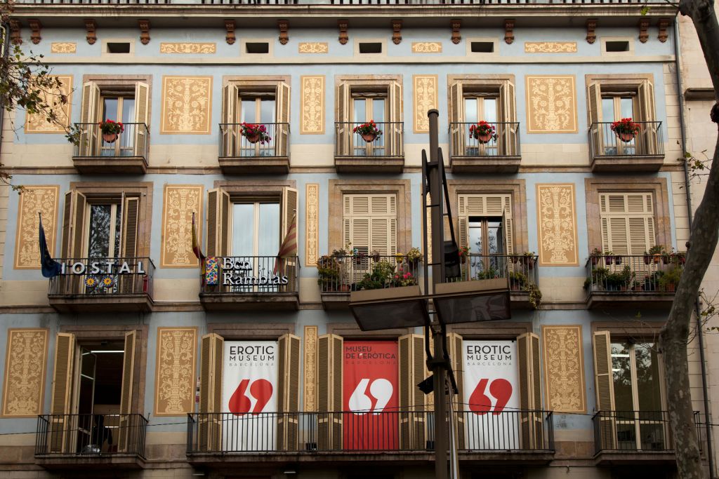 발코니, 화분, 에로틱 박물관 표지판이 있는 장식된 건물의 외관.