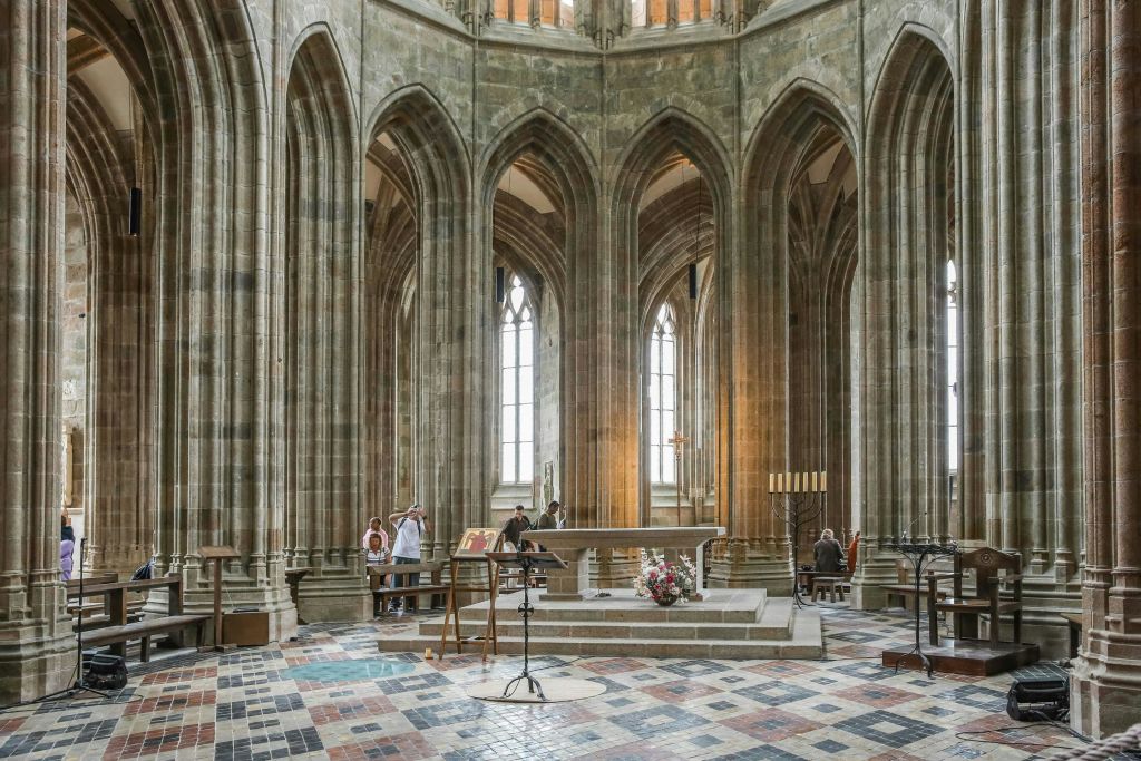 높은 아치형 기둥, 스테인드글라스 창문, 중앙 제단이 있는 화려하고 커다란 대성당 내부의 사람들.