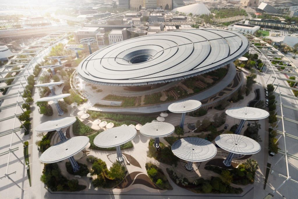 둥글고 높은 플랫폼과 녹지로 둘러싸인 커다란 원형 지붕이 있는 미래형 건물의 공중 전망.