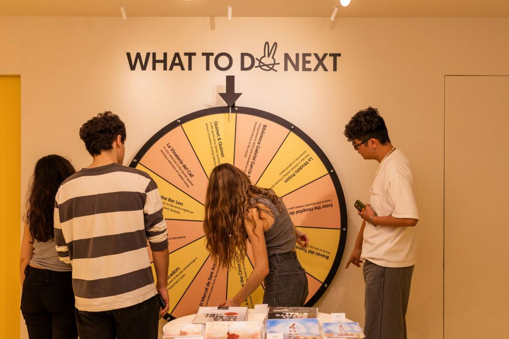 세 사람이 커다란 "다음 할 일" 휠 주위에 서서 그 위에 쓰여진 옵션을 가리키고 검사합니다.