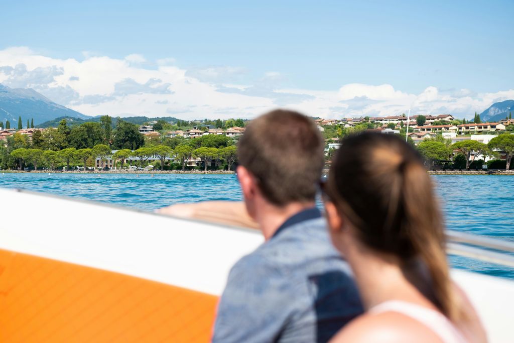 맑고 푸른 하늘 아래 배경으로 집과 나무가 보이는 호수에서 배를 타고 두 사람이 마주보고 있습니다.