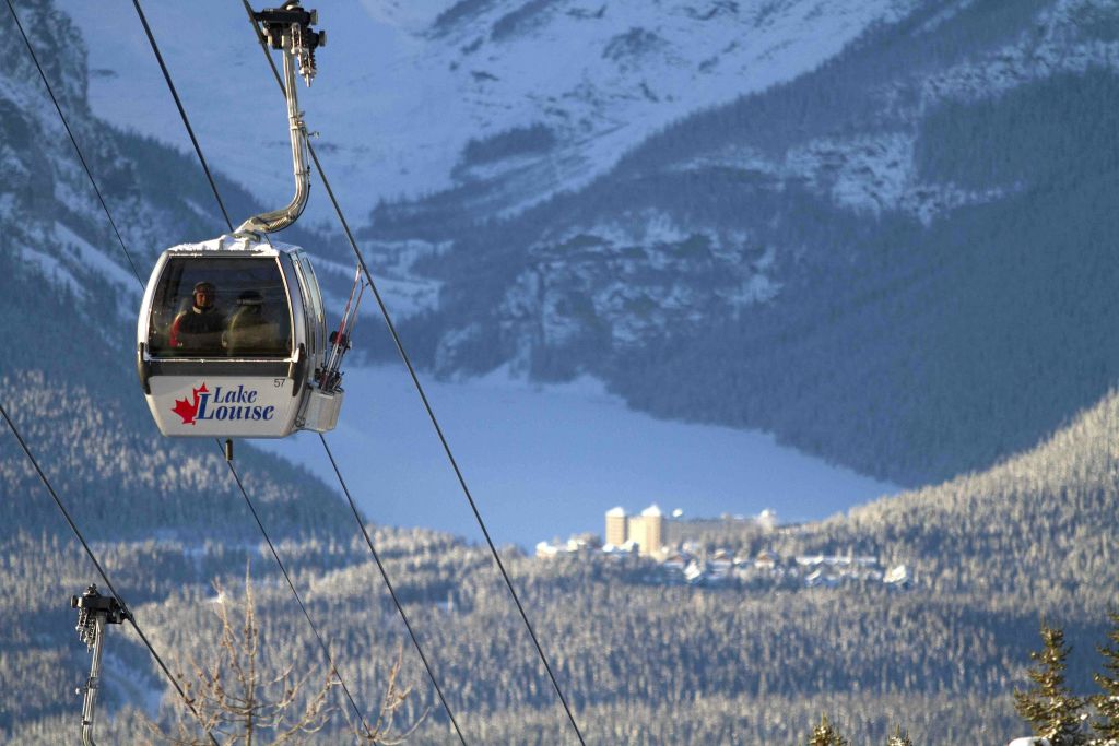 눈 덮인 산과 건물을 배경으로 "레이크 루이스" 라고 표시된 곤돌라가 올라갑니다.