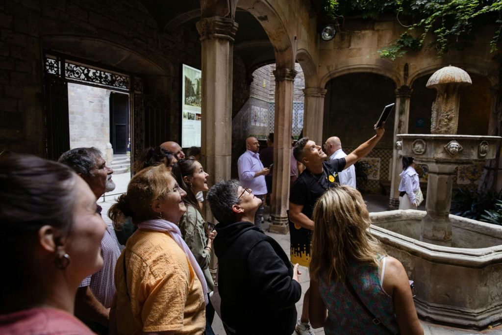 한 무리의 사람들이 역사적인 마당에 모여 한 사람이 태블릿을 들고 그룹을 안내했습니다.