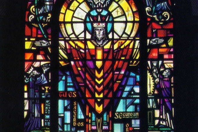 무늬와 상징으로 둘러싸인 종교적 인물이 묘사된 화려한 스테인드글라스 창문.