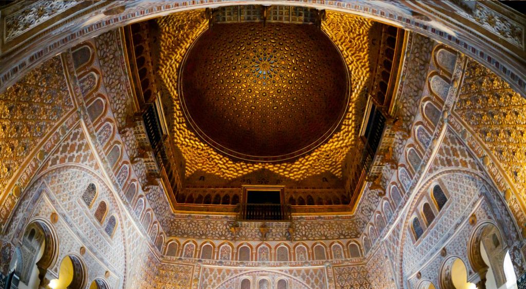 정교한 기하학적 패턴과 디테일한 아치, 발코니, 풍부한 색상으로 장식된 궁전 방의 화려한 돔형 천장.