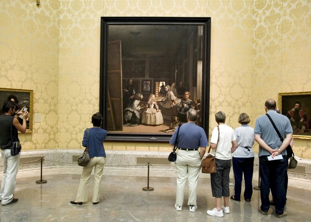 화려한 벽지가 있는 박물관의 대형 액자 그림 앞에 5명의 사람이 서 있습니다.