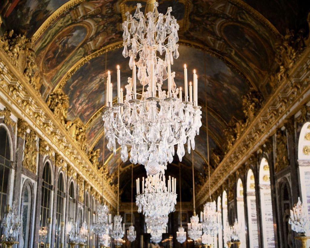 크리스탈 샹들리에, 골드 장식, 페인트 천장이 있는 화려한 홀로, 벽에 커다란 거울이 있습니다.